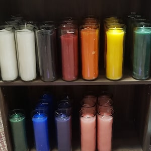 Peut inclure: Une étagère avec des rangées de pots de bougies en verre. Les bougies sont de différentes couleurs, notamment blanc, noir, rouge, orange, jaune, vert, bleu, violet et rose.