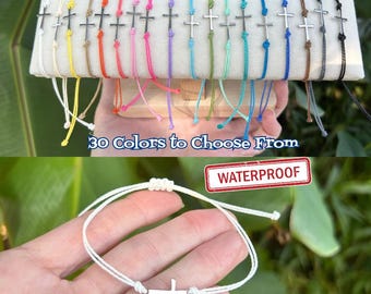 May include: A collection of adjustable cord bracelets featuring a small silver-toned cross charm. The bracelets are available in 30 colors, as indicated by the text. A single white bracelet is shown separately with the text WATERPROOF.