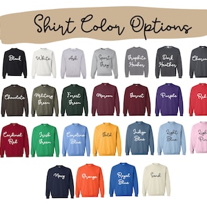 May include: A colour chart titled Shirt Color Options displaying twenty-two crewneck sweatshirts in various shades including black, white, ash, sport grey, graphite, dark heather, charcoal, chocolate, military green, forest green, maroon, garnet, purple, red, cardinal red, irish green, carolina blue, gold, indigo blue, light blue, light pink, navy, orange, royal blue, and sand.