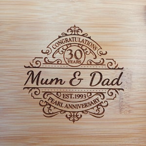 May include: A wooden chopping board with a laser engraved design celebrating a 30th anniversary. The design features the text "Congratulations Mum & Dad Est. 1993 Pearl Anniversary" with a decorative border and the number 30 in a circle.