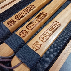Puede incluir: Cuatro palos de madera con correas de cuero negro y las palabras "PAUL SMITH" grabadas en ellos.