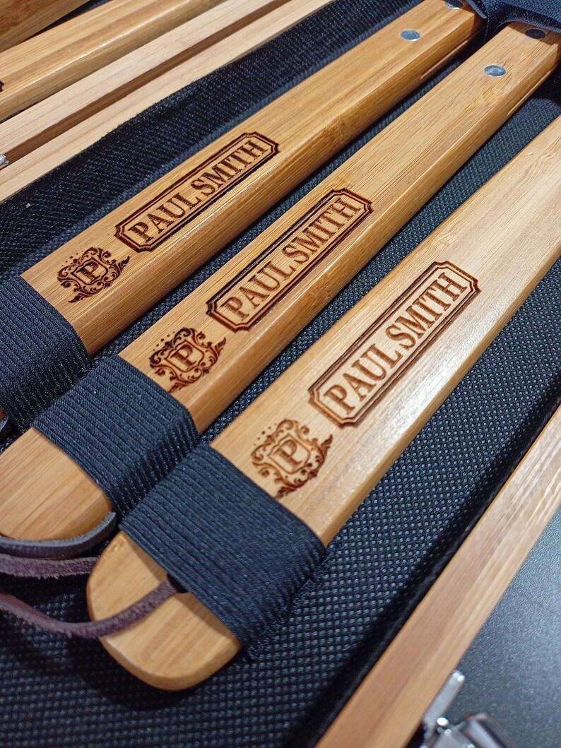 Puede incluir: Cuatro palos de madera con correas de cuero negro y las palabras "PAUL SMITH" grabadas en ellos.