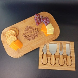 May include: A wooden cheese board with a personalised engraved message that reads "Congratulations 30 Years Mum & Dad Est. 1991 Pearl Anniversary". The board is accompanied by a set of four stainless steel cheese knives with wooden handles, all housed in a wooden case.