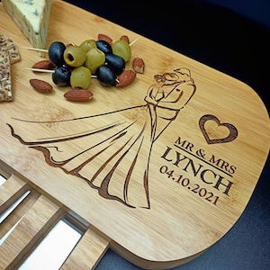 May include: A wooden cutting board with a knife holder and a design of a bride and groom. The board is engraved with the text "Mr. & Mrs. Lynch 04.10.2021".