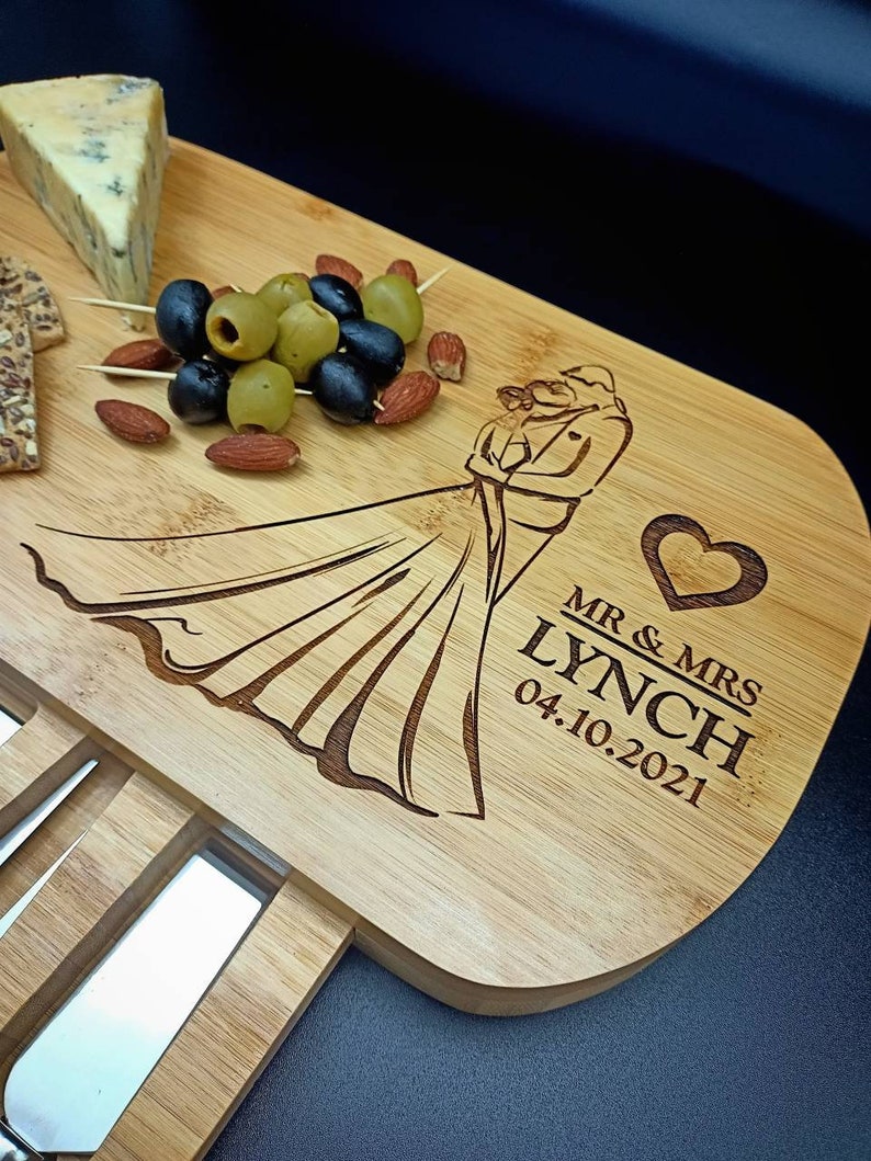 May include: A wooden cutting board with a knife holder and a design of a bride and groom. The board is engraved with the text "Mr. & Mrs. Lynch 04.10.2021".