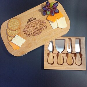 May include: A wooden cheese board with a personalized inscription celebrating a 60th anniversary. The inscription reads "Diamond Anniversary 60 Years 720 Months Mr & Mrs Roberts Est 1963". The board includes a set of four cheese knives with wooden handles.
