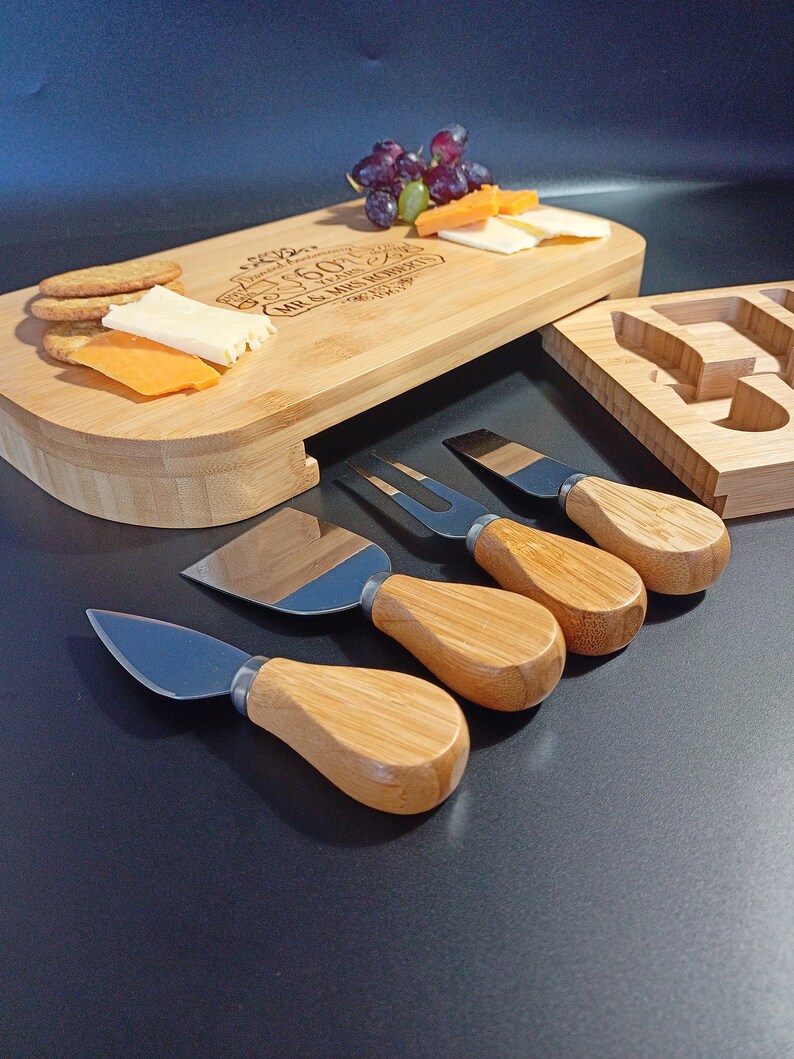 May include: A bamboo cheese board with a personalized inscription, "Celebrating 25 Years Mr. & Mrs. Roberts", and a set of four cheese knives with wooden handles. The board has a removable section for serving crackers and cheese.