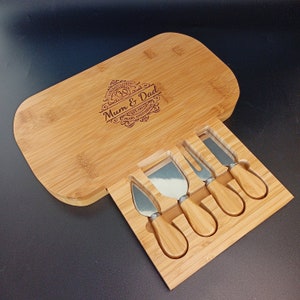 May include: A wooden cheese board with a set of knives. The board is engraved with the text "Congratulations Mum & Dad Est 1992 30th Pearl Anniversary".