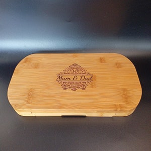 May include: A rectangular wooden serving tray with a raised edge and a hinged lid. The tray is made of light brown bamboo and has a dark brown engraved design that says "Congratulations 30 Years Mum & Dad Est. 1991 Pearl Anniversary".