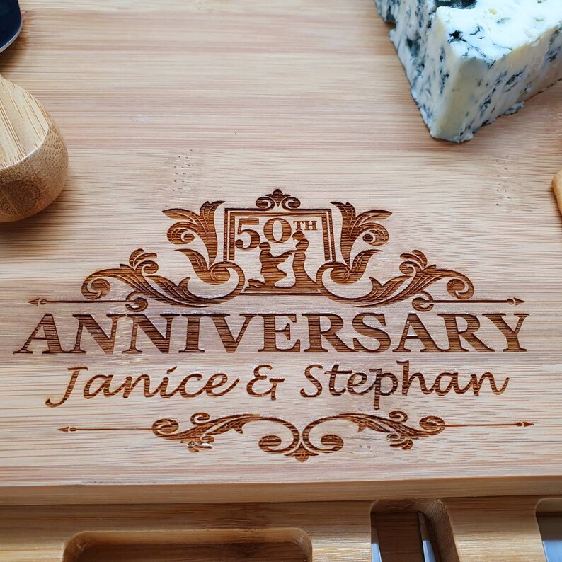 May include: A wooden cutting board with a personalized inscription for a 50th anniversary. The inscription reads "50th Anniversary Janice & Stephan".