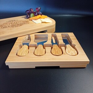 May include: A wooden cheese board with a personalized inscription, "50th Anniversary 50 Years Mr & Mrs Roberts 1967-2017", and a set of five stainless steel cheese knives with wooden handles.
