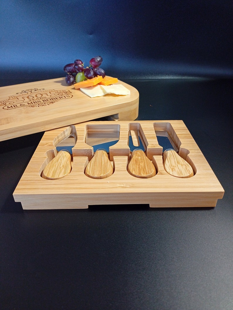 May include: A wooden cheese board with a personalized inscription, "50th Anniversary 50 Years Mr & Mrs Roberts 1967-2017", and a set of five stainless steel cheese knives with wooden handles.
