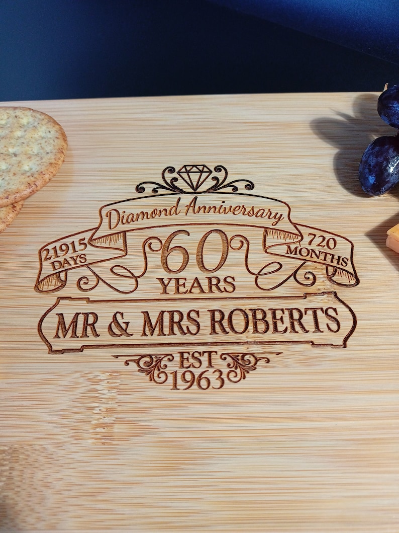 May include: A wooden cutting board with a diamond anniversary inscription. The inscription reads "Diamond Anniversary 60 Years Mr. & Mrs. Roberts Est. 1963" with a diamond graphic and ribbon banners.