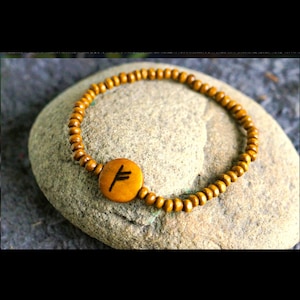 Peut inclure: Un bracelet en bois avec une perle en bois brun ornée du symbole Vegvisir, une rune directionnelle nordique, au centre.
