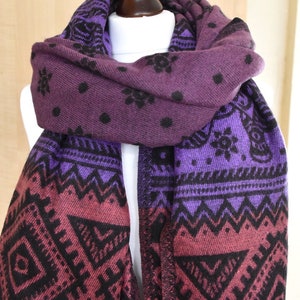 Peut inclure: Une écharpe à motifs violets et noirs avec un design géométrique. L'écharpe est faite d'un matériau doux et chaud, parfait pour vous garder au chaud en hiver.