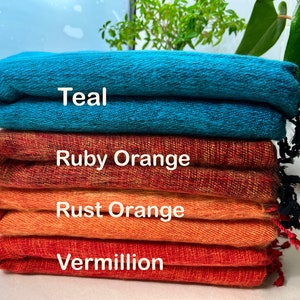 Puede incluir: Cuatro muestras de tela dobladas en tonos de turquesa, naranja rubí, naranja óxido y bermellón. Las muestras están apiladas una encima de la otra, con la muestra turquesa en la parte superior y la muestra bermellón en la parte inferior.