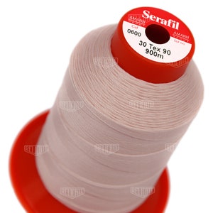 May include: A spool of pink thread labeled "Serafil" with the brand name "Amann Group" and the color code "0600". The spool also indicates the thread size as "30 Tex 90" and the length as "900m".