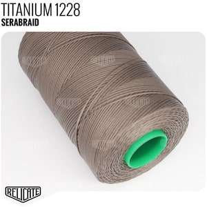 May include: A spool of brown thread labeled "TITANIUM 1228 SERABRAID". The thread is wound around a green plastic bobbin.