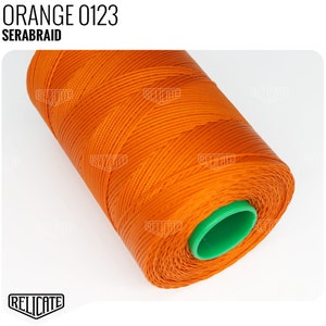 May include: A spool of orange thread labeled "ORANGE 0123 SERABRAID". The thread is wound around a green plastic spool.