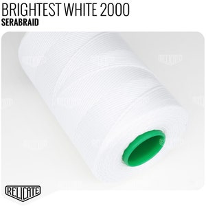 May include: A white spool of thread with a green plastic cap. The thread is labeled "BRIGHTEST WHITE 2000 SERABRAID".
