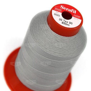 May include: A spool of gray thread labeled "Serafil" with the brand name "Amann Group" and the color number "3525". The spool also indicates the thread is 30 Tex 90 and 900 meters long.