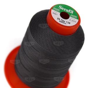 May include: A spool of black thread labeled "Serafil" with the brand name "Amann Group" and the details "Col. 8861", "Lot no. ZLZGA", "20 Tex 135", and "600m".
