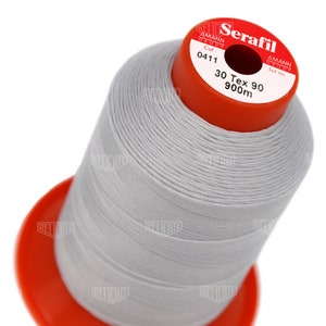 May include: A spool of white thread labeled "Serafil" with the brand name "Amann Group" and the color number "0411". The spool is labeled "30 Tex 90 900m".