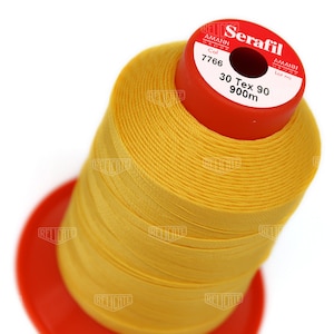 May include: A spool of bright yellow Serafil thread, with a red base and top. The label reads "Serafil 30 Tex 90 900m". This thread is likely used for sewing and crafting projects. The thread is tightly wound on the spool.