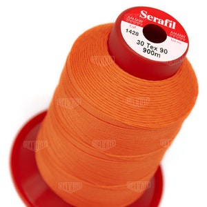 May include: A spool of bright orange Serafil thread, with a red base and top. The label reads "Serafil" and "30 Tex 90 900m". Ideal for sewing projects, this thread offers a vibrant color and is suitable for various fabrics.