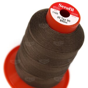 May include: A spool of brown thread labeled "Serafil 30 Tex 90 900m" by Amann Group. The spool is red and has a white label with the text "Col 1182" and "Lot no".