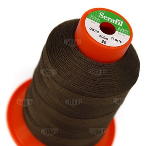 May include: A spool of brown thread labeled "Serafil" with the brand name "Amann Group" and the lot number "TLSH6". The spool is 600 meters long and is color number 0976.