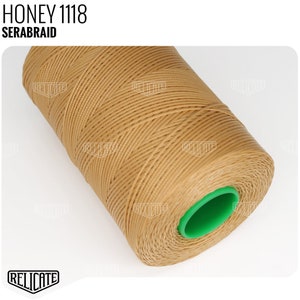 May include: A spool of honey-colored waxed thread, labeled "SERABRAID 1118 HONEY". The thread is wound around a green plastic bobbin.