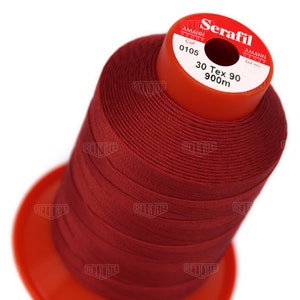 May include: A spool of red thread labeled "Serafil" by Amann Group. The spool is labeled "Col 0105", "30 Tex 90", and "900m".