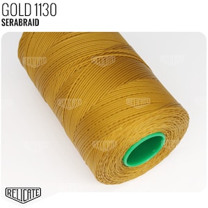 May include: A spool of gold colored thread labeled "GOLD 1130 SERABRAID".