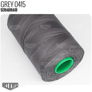 May include: A spool of grey thread labeled "GREY 0415 SERABRAID". The thread is wound around a green plastic spool.