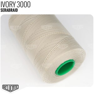 May include: A spool of ivory-colored thread, labeled "IVORY 3000 SERABRAID", with a green plastic end cap.