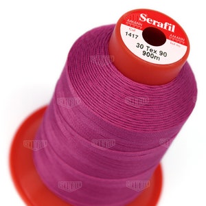 May include: A spool of pink thread labeled "Serafil" with the brand name "Amann Group" and the color number "1417". The spool is labeled "30 Tex 90 900m".