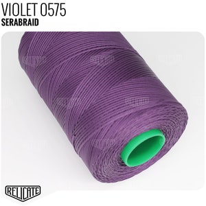 May include: A spool of purple thread labeled "VIOLET 0575 SERABRAID". The thread is wound around a green plastic bobbin.