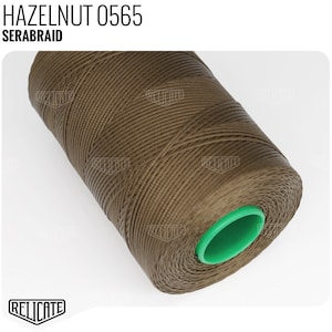 May include: A spool of brown thread with a green plastic center. The label on the spool reads "HAZELNUT 0565 SERABRAID".
