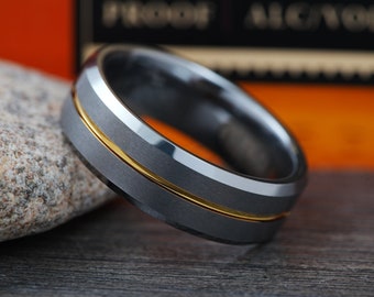 May include: A dark gray tungsten carbide ring with a gold band around the center. The ring has a beveled edge.