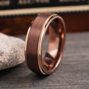 May include: A brushed rose gold tungsten carbide ring with a beveled edge and a polished inner band.