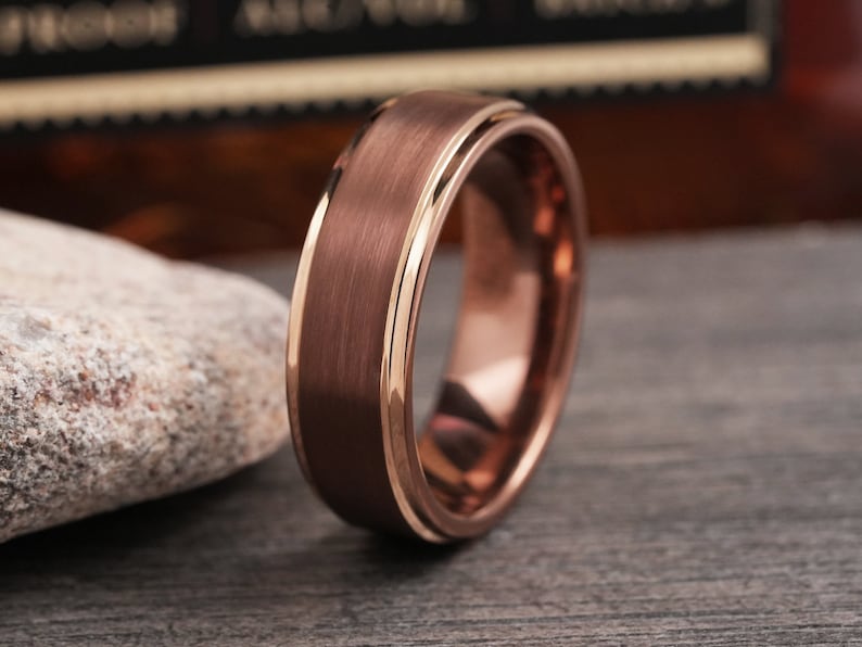 May include: A brushed rose gold tungsten carbide ring with a beveled edge and a polished inner band.