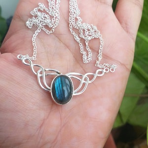 May include: A silver necklace with a blue labradorite gemstone pendant. The pendant is set in a delicate silver design.