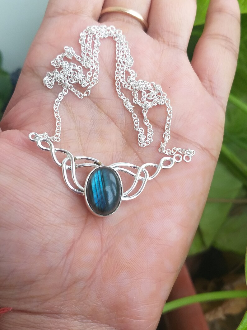 May include: A silver necklace with a blue labradorite gemstone pendant. The pendant is set in a delicate silver design.