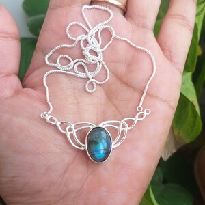 May include: A silver necklace with a blue labradorite gemstone pendant. The pendant is set in a silver Celtic knot design.