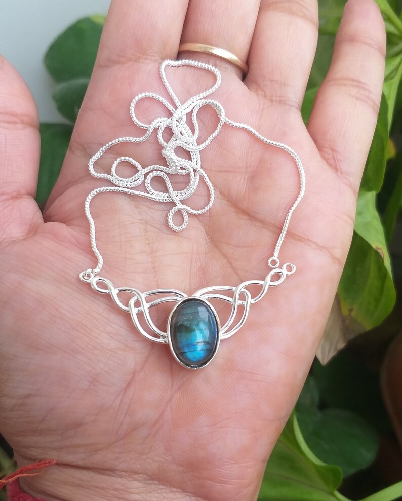 May include: A silver necklace with a blue labradorite gemstone pendant. The pendant is set in a silver Celtic knot design.