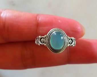 May include: A silver ring with an oval-shaped light blue gemstone set in a decorative silver band.