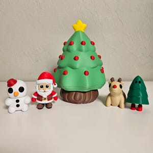 Könnte beinhalten: Eine Sammlung von Weihnachtsfiguren. Enthält einen Schneemann, den Weihnachtsmann, einen Weihnachtsbaum mit roten Ornamenten, ein Rentier und einen zweiten Weihnachtsbaum. Die Figuren sind in verschiedenen Farben gehalten, darunter Weiß, Rot, Grün und Braun.