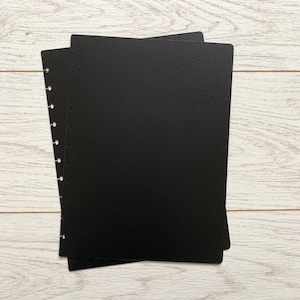 May include: Two black disc bound notebooks with a row of holes down the side.