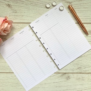 May include: A white planner with a weekly layout, featuring days of the week from Monday to Friday. The planner has a notes section and is open to reveal the pages. The planner is on a white wooden surface with a rose and a pen.